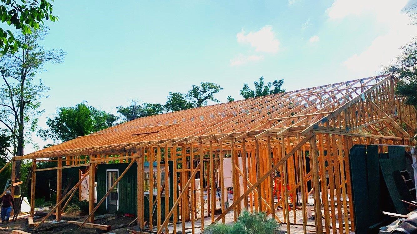 Wooden frame structure of a house under construction with trees in the background.